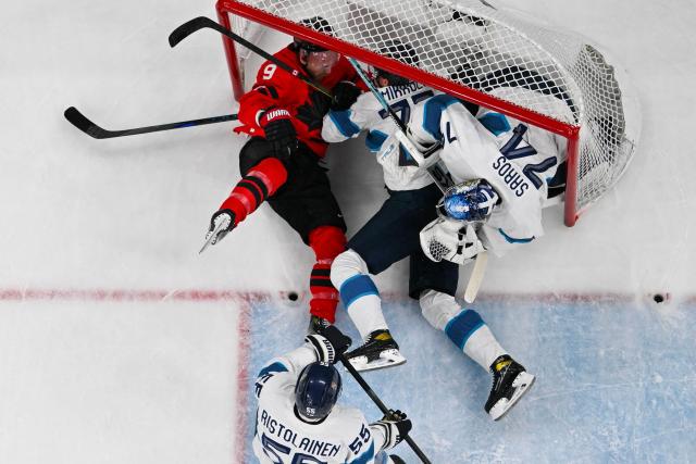 Canada's #09 Sam Bennett (L) collides into the net with Finland's #77 Niko Mikkola (C) and Finland's #74 Juuse Saros during the men's play-off semi-final ice hockey match between Canada and Finland at the Milano Santagiulia Ice Hockey Arena during the Milano Cortina 2026 Winter Olympic Games in Milan, on February 20, 2026. (Photo by JULIEN DE ROSA / AFP)