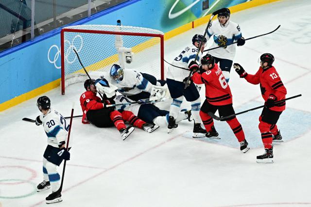 Canada's #09 Sam Bennett (L) and Finland's #77 Niko Mikkola (2nd L) fall into the goal  during the men's play-off semi-final ice hockey match between Canada and Finland at the Milano Santagiulia Ice Hockey Arena during the Milano Cortina 2026 Winter Olympic Games in Milan, on February 20, 2026. (Photo by JULIEN DE ROSA / AFP)