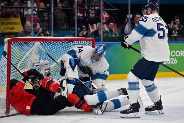 (LtoR) Canada's #09 Sam Bennett, Finland's #77 Niko Mikkola and Finland's #74 Juuse Saros dislodge the goal as Finland's #55 Rasmus Ristolainen looks on during the men's play-off semi-final ice hockey match between Canada and Finland at the Milano Santagiulia Ice Hockey Arena during the Milano Cortina 2026 Winter Olympic Games in Milan, on February 20, 2026. (Photo by Alexander NEMENOV / AFP)