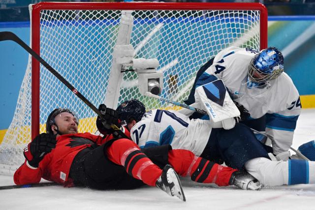 (LtoR) Canada's #09 Sam Bennett, Finland's #77 Niko Mikkola and Finland's #74 Juuse Saros dislodge the goal during the men's play-off semi-final ice hockey match between Canada and Finland at the Milano Santagiulia Ice Hockey Arena during the Milano Cortina 2026 Winter Olympic Games in Milan, on February 20, 2026. (Photo by Alexander NEMENOV / AFP)