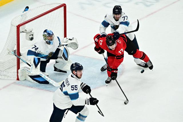 Canada's #17 Macklin Celebrini (C) fights for the puck with Finland's #77 Niko Mikkola (up) and Finland's #74 Juuse Saros (L)  during the men's play-off semi-final ice hockey match between Canada and Finland at the Milano Santagiulia Ice Hockey Arena during the Milano Cortina 2026 Winter Olympic Games in Milan, on February 20, 2026. (Photo by JULIEN DE ROSA / AFP)
