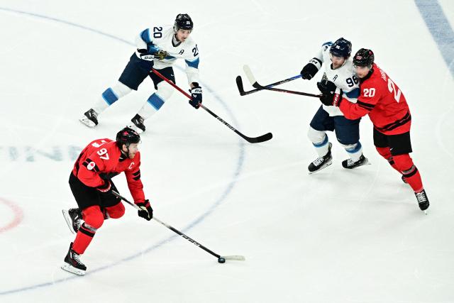 Canada's #97 Connor Mcdavid (L) skates with the puck  during the men's play-off semi-final ice hockey match between Canada and Finland at the Milano Santagiulia Ice Hockey Arena during the Milano Cortina 2026 Winter Olympic Games in Milan, on February 20, 2026. (Photo by JULIEN DE ROSA / AFP)