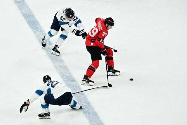 Canada's #29 Nathan Mackinnon (R) fights for the puck with Finland's #62 Artturi Lehkonen (C)  during the men's play-off semi-final ice hockey match between Canada and Finland at the Milano Santagiulia Ice Hockey Arena during the Milano Cortina 2026 Winter Olympic Games in Milan, on February 20, 2026. (Photo by JULIEN DE ROSA / AFP)