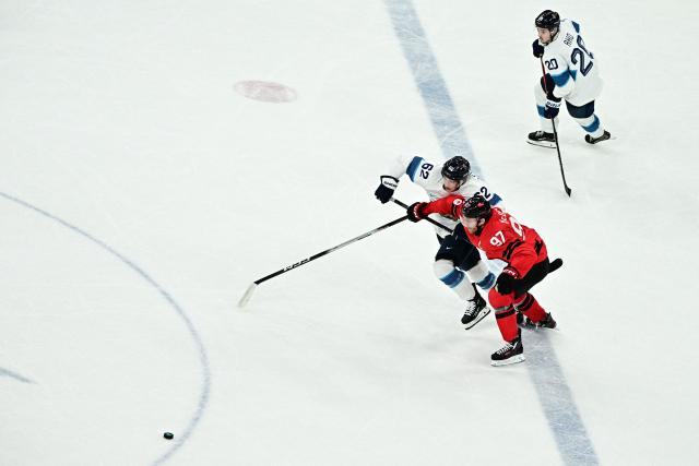 Finland's #62 Artturi Lehkonen (L) fights for the puck with Canada's #97 Connor Mcdavid  during the men's play-off semi-final ice hockey match between Canada and Finland at the Milano Santagiulia Ice Hockey Arena during the Milano Cortina 2026 Winter Olympic Games in Milan, on February 20, 2026. (Photo by JULIEN DE ROSA / AFP)
