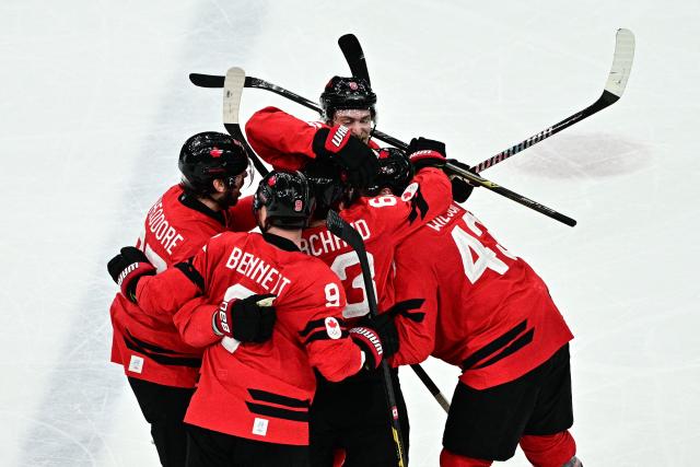 Canada's #27 Shea Theodore (L) celebrates with teammates after scoring his team's second goal during the men's play-off semi-final ice hockey match between Canada and Finland at the Milano Santagiulia Ice Hockey Arena during the Milano Cortina 2026 Winter Olympic Games in Milan, on February 20, 2026. (Photo by JULIEN DE ROSA / AFP)
