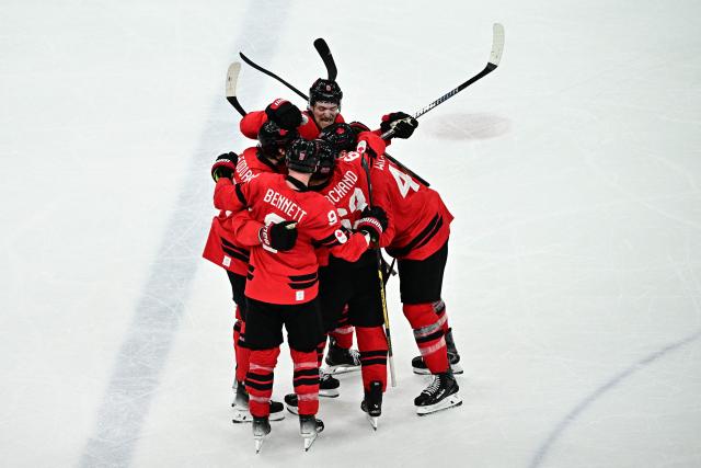 Canada's #27 Shea Theodore (L) celebrates with  teammates after scoring his team's second goal during the men's play-off semi-final ice hockey match between Canada and Finland at the Milano Santagiulia Ice Hockey Arena during the Milano Cortina 2026 Winter Olympic Games in Milan, on February 20, 2026. (Photo by JULIEN DE ROSA / AFP)