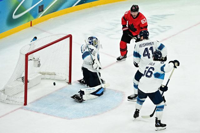 Canada's #63 Brad Marchand (C) reacts as  Finland's #74 Juuse Saros (L) concedes Canada's second goal  during the men's play-off semi-final ice hockey match between Canada and Finland at the Milano Santagiulia Ice Hockey Arena during the Milano Cortina 2026 Winter Olympic Games in Milan, on February 20, 2026. (Photo by JULIEN DE ROSA / AFP)