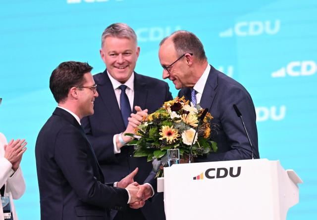 German Chancellor and Chairman of the Christian Democratic Party (CDU) Friedrich Merz (R) is congratulated by regional leader of the CDU in the southern state of Baden-Wuerttemberg Manuel Hagel (L) after he was re-elected as party Chairman at the CDU party Congress at the fair grounds in Stuttgart, southern Germany, on February 20, 2026. (Photo by THOMAS KIENZLE / AFP)