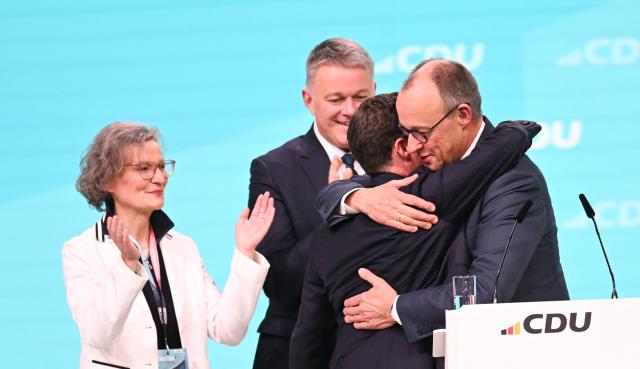 German Chancellor and Chairman of the Christian Democratic Party (CDU) Friedrich Merz (R) is congratulated by regional leader of the CDU in the southern state of Baden-Wuerttemberg Manuel Hagel (C) after he was re-elected as party Chairman at the CDU party Congress at the fair grounds in Stuttgart, southern Germany, on February 20, 2026. (Photo by THOMAS KIENZLE / AFP)