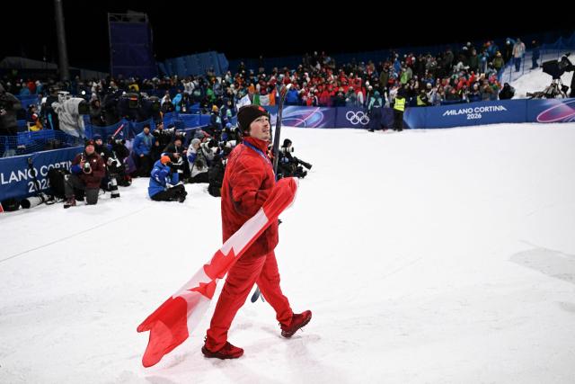 Canada's Brendan Mackay walks with the Canadian flag after the medal ceremony of the freestyle skiing men's freeski halfpipe final during the Milano Cortina 2026 Winter Olympic Games at Livigno Snow Park, in Livigno (Valtellina), on February 20, 2026. (Photo by Kirill KUDRYAVTSEV / AFP)