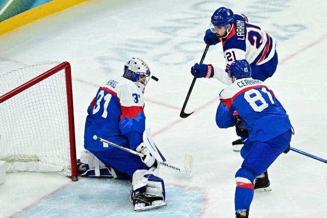 Slovakia's #31 Samuel Hlavaj (L) makes a save from a shot by USA's #21 Dylan Larkin during the men's play-off semi-final ice hockey match between USA and Slovakia at the Milano Santagiulia Ice Hockey Arena during the Milano Cortina 2026 Winter Olympic Games in Milan, on February 20, 2026. (Photo by JULIEN DE ROSA / AFP)