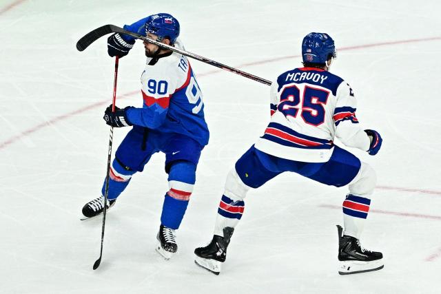 Slovakia's #90 Tomas Tatar (L) grimaces as he is struck by USA's #25 Charlie McAvoy's stick during the men's play-off semi-final ice hockey match between USA and Slovakia at the Milano Santagiulia Ice Hockey Arena during the Milano Cortina 2026 Winter Olympic Games in Milan, on February 20, 2026. (Photo by JULIEN DE ROSA / AFP)