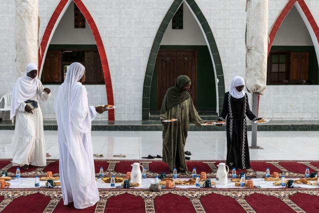 Muslim women place down plates of food ahead of breaking fast during the first Friday of the holy month of Ramadan at the Mosque of the Divinity in Dakar, on February 20, 2026. Muslims throughout the world are marking the month of Ramadan, the holiest month in the Islamic calendar, during which devotees fast from dawn until dusk. (Photo by PATRICK MEINHARDT / AFP)