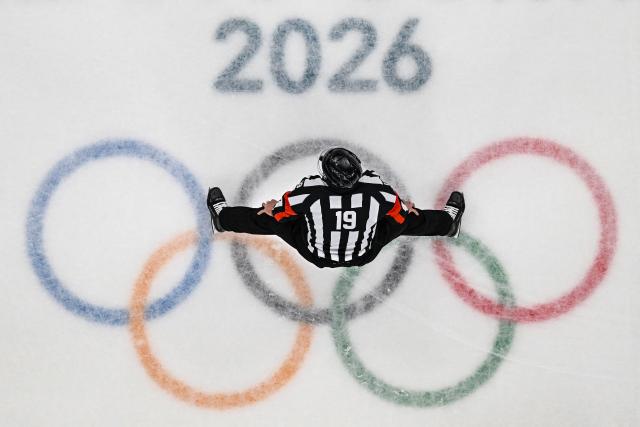 A referee tands over the Olympic logo  during the men's play-off semi-final ice hockey match between USA and Slovakia at the Milano Santagiulia Ice Hockey Arena during the Milano Cortina 2026 Winter Olympic Games in Milan, on February 20, 2026. (Photo by JULIEN DE ROSA / AFP)