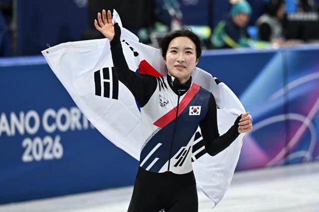 Gold medallist South Korea's Kim Gil-li celebrates with a flag of South Korea after the short track speed skating women's 1500m final during the Milano Cortina 2026 Winter Olympic Games at Milano Ice Skating Arena in Milan on February 20, 2026. (Photo by Gabriel BOUYS / AFP)