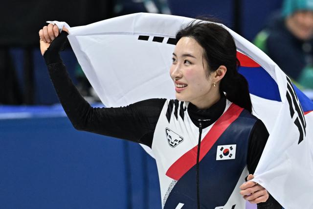 Gold medallist South Korea's Kim Gil-li celebrates with a flag of South Korea after the short track speed skating women's 1500m final during the Milano Cortina 2026 Winter Olympic Games at Milano Ice Skating Arena in Milan on February 20, 2026. (Photo by Gabriel BOUYS / AFP)