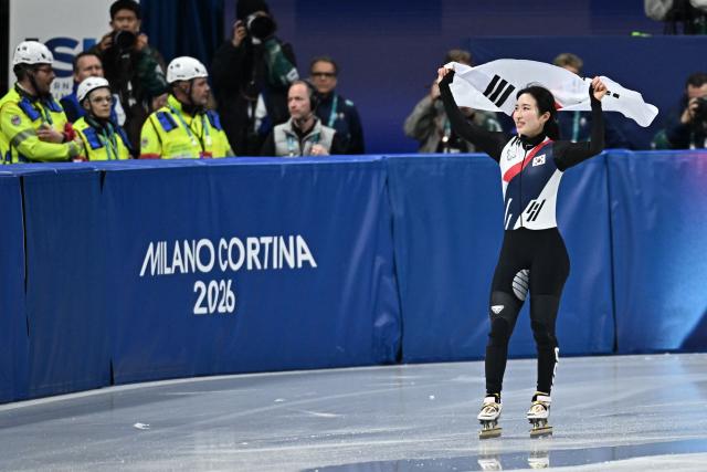 Gold medallist South Korea's Kim Gil-li celebrates with a flag of South Korea after the short track speed skating women's 1500m final during the Milano Cortina 2026 Winter Olympic Games at Milano Ice Skating Arena in Milan on February 20, 2026. (Photo by Gabriel BOUYS / AFP)