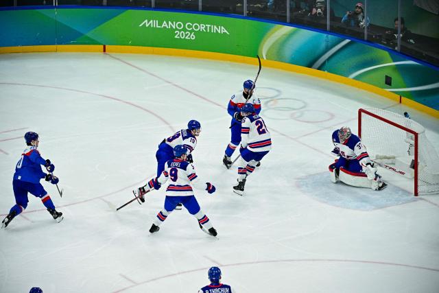 Slovakia's #20 Juraj Slafkovsky (L) scores their first goal during the men's play-off semi-final ice hockey match between USA and Slovakia at the Milano Santagiulia Ice Hockey Arena during the Milano Cortina 2026 Winter Olympic Games in Milan, on February 20, 2026. (Photo by JULIEN DE ROSA / AFP)