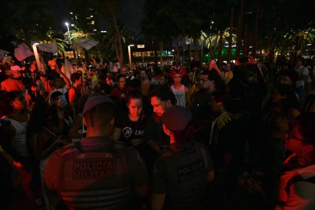 Military Police officers speak with protesters from the Guarani ethnic group and environmental activists during a demonstration against dredging in the Amazon outside the headquarters of US agribusiness giant Cargill in Sao Paulo, Brazil, on February 20, 2026. (Photo by NELSON ALMEIDA / AFP)
