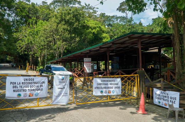 This general view shows the entrance of Tayrona National Park with banners reading ‘Closed’, ‘United for the reconstruction of the social fabric in the territory’ and ‘Peasant, Indigenous and Afro-Colombian communities united’ in the municipality of Santa Marta, Magdalena department, Colombia, on February 20, 2026. Defense Minister Pedro Sanchez said that extortion and pressure from ‘Los Pachenca’, a paramilitary group also known as the Conquistador Self-Defense Forces of the Sierra Nevada, forced the temporary closure of the park. (Photo by Randy Montenegro / AFP)