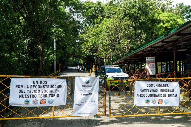 This general view shows the entrance of Tayrona National Park with banners reading ‘Closed’, ‘United for the reconstruction of the social fabric in the territory’ and ‘Peasant, Indigenous and Afro-Colombian communities united’ in the municipality of Santa Marta, Magdalena department, Colombia, on February 20, 2026. Defense Minister Pedro Sanchez said that extortion and pressure from ‘Los Pachenca’, a paramilitary group also known as the Conquistador Self-Defense Forces of the Sierra Nevada, forced the temporary closure of the park. (Photo by Randy Montenegro / AFP)