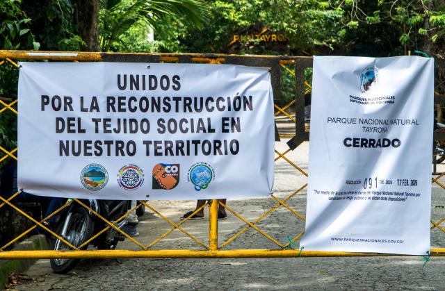 This general view shows the entrance of Tayrona National Park with banners reading ‘Closed’ and ‘United for the reconstruction of the social fabric in the territory’ in the municipality of Santa Marta, Magdalena department, Colombia, on February 20, 2026. Defense Minister Pedro Sanchez said that extortion and pressure from ‘Los Pachenca’, a paramilitary group also known as the Conquistador Self-Defense Forces of the Sierra Nevada, forced the temporary closure of the park. (Photo by Randy Montenegro / AFP)