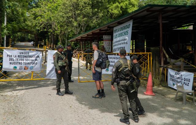 A member of the Colombian national police talks with a tourist at the entrance of Tayrona National Park in the municipality of Santa Marta, Magdalena department, Colombia, on February 20, 2026. Defense Minister Pedro Sanchez said that extortion and pressure from ‘Los Pachenca’, a paramilitary group also known as the Conquistador Self-Defense Forces of the Sierra Nevada, forced the temporary closure of the park. (Photo by Randy Montenegro / AFP)