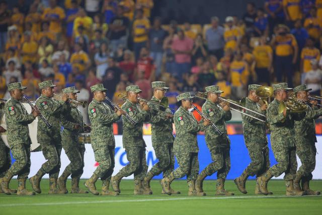 Soldiers perform honors for Flag Day before the Liga MX Clausura football match between Tigres and Pachuca at the University Stadium (UANL) in Monterrey, Mexico, on February 20, 2026. (Photo by Julio Cesar AGUILAR / AFP)