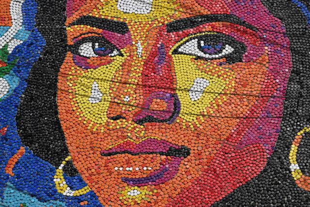 A mural made with plastic bottle caps by Venezuelan artist Oscar Olivares is seen on an apartment building in the Zacamil neighborhood in Mejicanos, El Salvador, on February 20, 2026. The artwork, over 13 meters tall and made with more than 100,000 recycled plastic bottle caps, is regarded as the world's tallest bottle-cap mural. The piece reinterprets the Mona Lisa with a Latin American identity and pays tribute to Salvadoran women. (Photo by Marvin RECINOS / AFP)