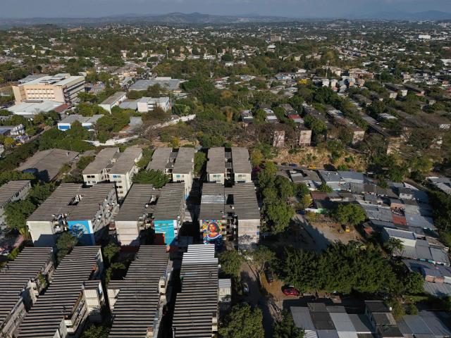 Aerial view of a mural made with plastic bottle caps by Venezuelan artist Oscar Olivares on an apartment building in the Zacamil neighborhood in Mejicanos, El Salvador, on February 20, 2026. The artwork, over 13 meters tall and made with more than 100,000 recycled plastic bottle caps, is regarded as the world's tallest bottle-cap mural. The piece reinterprets the Mona Lisa with a Latin American identity and pays tribute to Salvadoran women. (Photo by Marvin RECINOS / AFP)