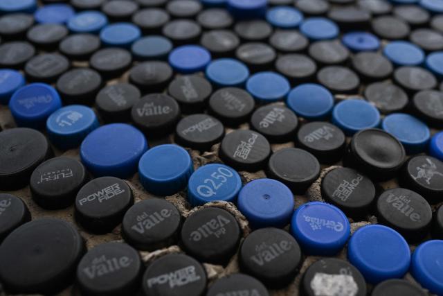 Detail of a mural made with plastic bottle caps by Venezuelan artist Oscar Olivares on an apartment building in the Zacamil neighborhood in Mejicanos, El Salvador, on February 20, 2026. The artwork, over 13 meters tall and made with more than 100,000 recycled plastic bottle caps, is regarded as the world's tallest bottle-cap mural. The piece reinterprets the Mona Lisa with a Latin American identity and pays tribute to Salvadoran women. (Photo by Marvin RECINOS / AFP)