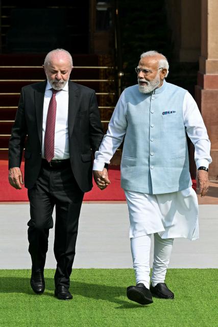 India's Prime Minister Narendra Modi (R) holds hands with Brazil's President Luiz Inacio Lula da Silva as they walk before their meeting at the Hyderabad House in New Delhi on February 21, 2026. (Photo by Sajjad HUSSAIN / AFP)