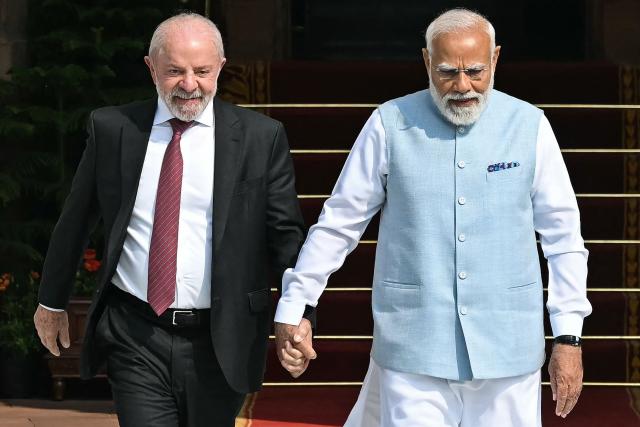India's Prime Minister Narendra Modi (R) holds hands with Brazil's President Luiz Inacio Lula da Silva as they walk before their meeting at the Hyderabad House in New Delhi on February 21, 2026. (Photo by Sajjad HUSSAIN / AFP)