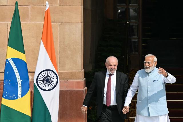 India's Prime Minister Narendra Modi (R) holds hands with Brazil's President Luiz Inacio Lula da Silva as they walk before their meeting at the Hyderabad House in New Delhi on February 21, 2026. (Photo by Sajjad HUSSAIN / AFP)