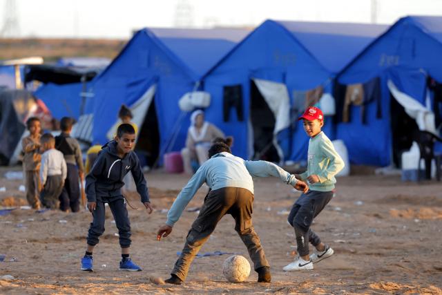 Children play football next to tent shelters at a relief camp for those affected by floods that struck northern and western Morocco, in the Kenitra region on February 20, 2026. (Photo by Abdel Majid BZIOUAT / AFP)