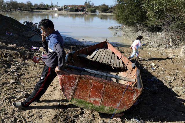 A man leans by a boat used to cross the water following floods that struck northern and western Morocco, in the Kenitra region on February 20, 2026. (Photo by Abdel Majid BZIOUAT / AFP)