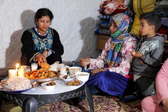 Members of a family sit to break their fast together for the "iftar" meal during the Muslim holy month of Ramadan in a tent shelter at a relief camp for those affected by floods that struck northern and western Morocco, in the Kenitra region on February 20, 2026. (Photo by Abdel Majid BZIOUAT / AFP)