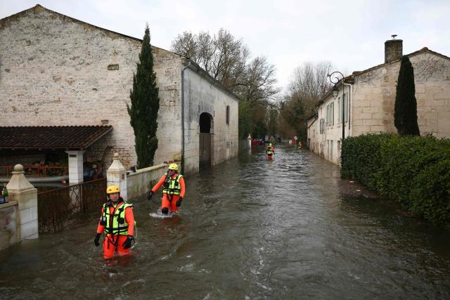 Sea rescuers walk in a flooded street while taking part in a rescue operation to evacuate isolated residents in Courcoury, south-western France on February 21, 2026. Météo-France has extended flood alerts for February 18 and February 19, 2026 : red for Loire-Atlantique, Charente-Maritime and Maine-et-Loire, and orange in nine other departments in the west, while noting that the dry weather should help the waters recede. (Photo by ROMAIN PERROCHEAU / AFP)