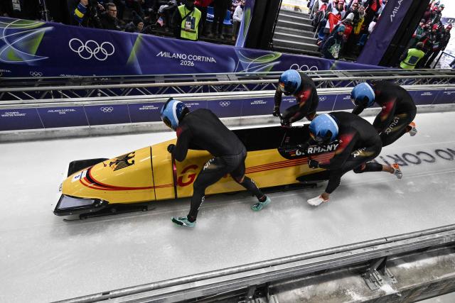 Germany's Adam Ammour, Germany's Issam Ammour, Germany's Joshua Tasche and Germany's Alexander Schaller compete in  the bobsleigh men's 4-man heat 1 at Cortina Sliding Centre during the Milano Cortina 2026 Winter Olympic Games in Cortina d'Ampezzo on February 21, 2026. (Photo by Tiziana FABI / AFP)