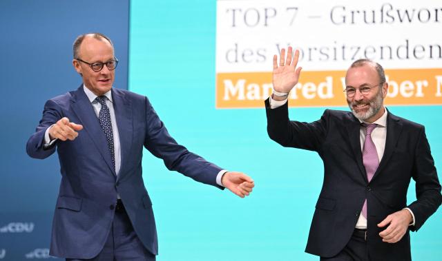 German Chancellor and leader of Germany's Christian Democratic Union (CDU) Friedrich Merz (L) reacts after Manfred Weber, chairman of the European People's Party (EPP) delivered his speech at the party congress of Germany's Christian Democratic Union (CDU) in Stuttgart, southern Germany, on February 21, 2026. (Photo by THOMAS KIENZLE / AFP)