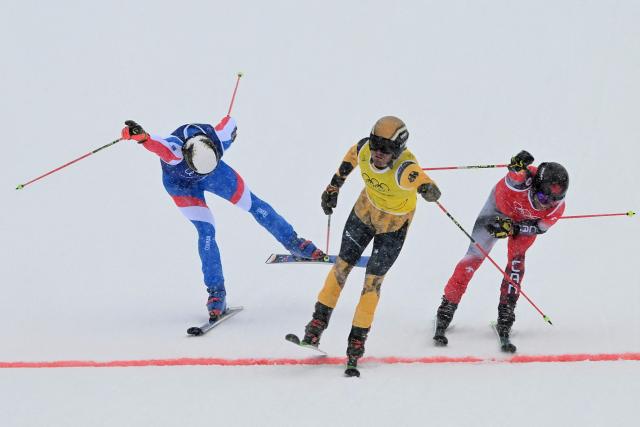 (L-R) France's Evan Klufts, Germany's Tim Hronek and Canada's Kevin Drury cross the finish-line in the freestyle skiing men's ski cross 1/8 final 7 during the Milano Cortina 2026 Winter Olympic Games at Livigno Snow Park, in Livigno (Valtellina), on February 21, 2026. (Photo by Kirill KUDRYAVTSEV / AFP)
