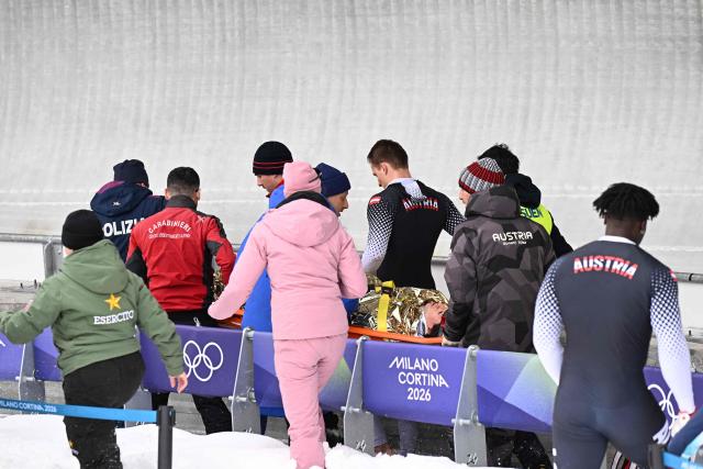Austria's Jakob Mandlbauer is brought off on a stretcher after a crash in the bobsleigh men's 4-man heat 2 at Cortina Sliding Centre during the Milano Cortina 2026 Winter Olympic Games in Cortina d'Ampezzo on February 21, 2026. (Photo by Tiziana FABI / AFP)