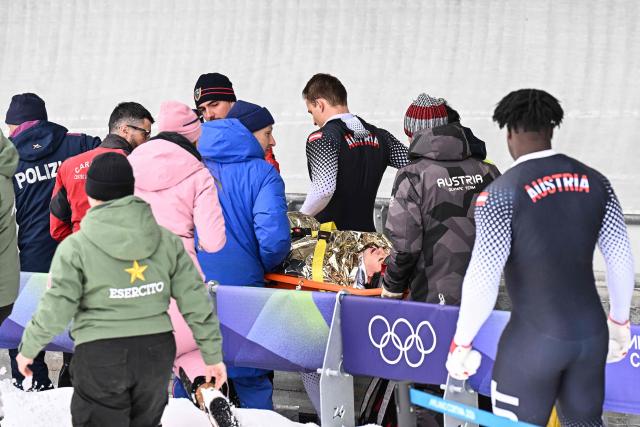 Austria's Jakob Mandlbauer is brought off on a stretcher after a crash in the bobsleigh men's 4-man heat 2 at Cortina Sliding Centre during the Milano Cortina 2026 Winter Olympic Games in Cortina d'Ampezzo on February 21, 2026. (Photo by Tiziana FABI / AFP)