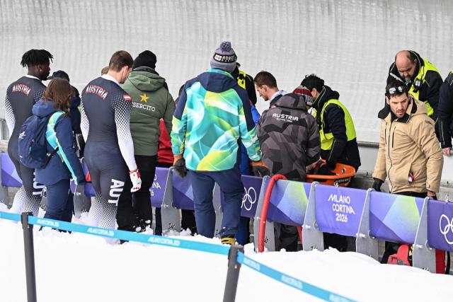 Austria's Jakob Mandlbauer is brought off on a stretcher after a crash in the bobsleigh men's 4-man heat 2 at Cortina Sliding Centre during the Milano Cortina 2026 Winter Olympic Games in Cortina d'Ampezzo on February 21, 2026. (Photo by Tiziana FABI / AFP)
