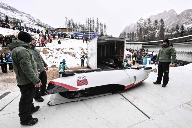 Track tenants remove the sled of Trinidad and Tobago's Axel Brown, Trinidad and Tobago's De Aundre John, Trinidad and Tobago's Shakeel John and Trinidad and Tobago's Xaverri Williams after a crash in the bobsleigh men's 4-man heat 2 at Cortina Sliding Centre during the Milano Cortina 2026 Winter Olympic Games in Cortina d'Ampezzo on February 21, 2026. (Photo by Tiziana FABI / AFP)