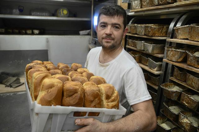 French volunteer baker Loic Nervi holds a basket of freshly baked bread in his mobile bakery to distribute among residents of a temporary dwelling for people who lost their homes and internally displaced people in Borodyanka, Kyiv region on February 19, 2026, amid the Russian invasion of Ukraine. While Ukraine regularly faces power and heating cuts due to Russian strikes, Loic Nervi
works alone from early morning to bake around 700 loaves of bread a day, attracting dozens of locals to his white truck. Over multiple missions across Ukraine, he says he has distributed tens of thousands of loaves, most often to elderly residents left without family support. (Photo by Genya SAVILOV / AFP)