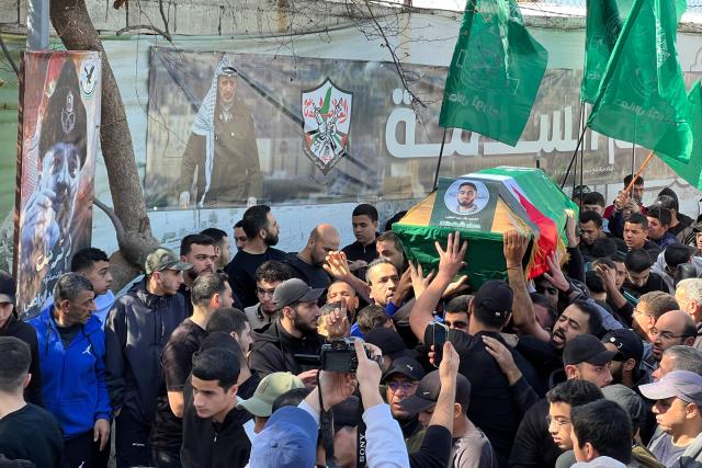 Mourners carry one of two coffins past an image of the later Palestinian leader Yasser Arafat, the day after two people were killed in an Israeli strike on the Palestinian refugee camp in Ain al-Hilweh, near the coastal city of Sidon, in southern Lebanon on February 21, 2026. Lebanon's health ministry said 10 people were killed on February 20, 2026, in the east and two in the south of the country both areas where Hezbollah holds sway. The strikes come as tensions are brewing between the United States and Iran, with the US president threatening military action over the Islamic republic's nuclear programme. (Photo by Mahmoud ZAYYAT / AFP)