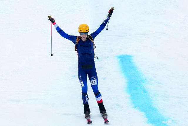 France's Thibault Anselmet celebrates as he crosses the finish line to win the mixed relay ski mountaineering race during the Milano Cortina 2026 Winter Olympic Games at the Stelvio Ski Centre in Bormio (Valtellina) on February 21, 2026. (Photo by Dimitar DILKOFF / AFP)
