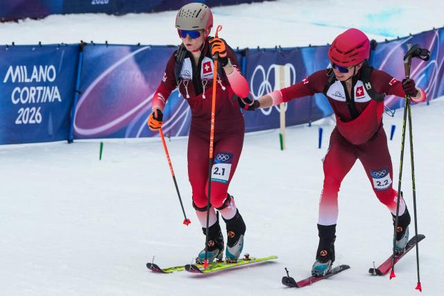 Switzerland's Jon Kistler (R) hand over to Switzerland's Marianne Fatton (L) as they competes in the mixed relay ski mountaineering race during the Milano Cortina 2026 Winter Olympic Games at the Stelvio Ski Centre in Bormio (Valtellina) on February 21, 2026. (Photo by Dimitar DILKOFF / AFP)