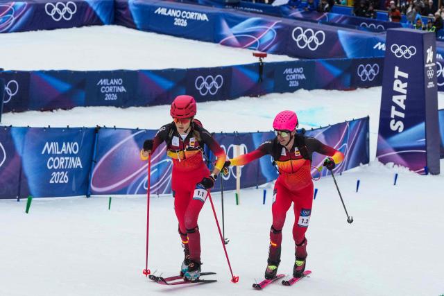 Spain's Oriol Cardona Coll (R) hands over to Spain's Ana Alonso Rodriguez ast they compete in the mixed relay ski mountaineering race during the Milano Cortina 2026 Winter Olympic Games at the Stelvio Ski Centre in Bormio (Valtellina) on February 21, 2026. (Photo by Dimitar DILKOFF / AFP)